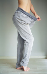 Diet concept. Slim girl after diet in old big jeans