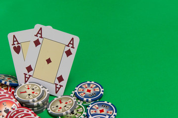 poker chips stack and playing cards on green table. empty space for text and design. two aces