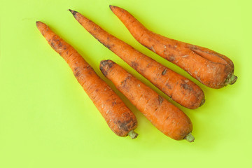 Ugly food. Deformed organic carrots on the pastel yellow background. Bright colors, copy space.