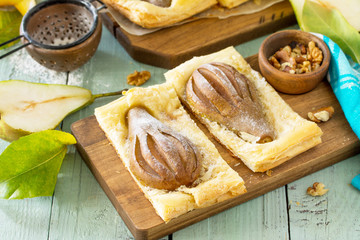 Summer dessert. Homemade Cake Puff Pastry with Pear and Stuffed with Nut Cream a rustic wooden table.