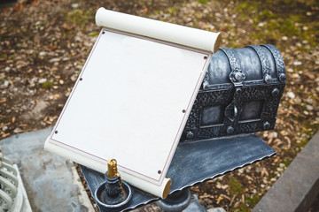 White scroll with copy space, lying on the mailbox against the background of autumn foliage on the ground.