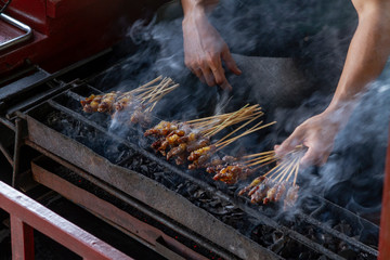 Chicken satay grill at a busy street food market	