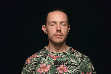 Obraz premium Close up portrait of young man isolated on black studio background. Photoshot of real emotions of male model with closed eyes. Thoughtful. Facial expression, human nature and emotions concept.