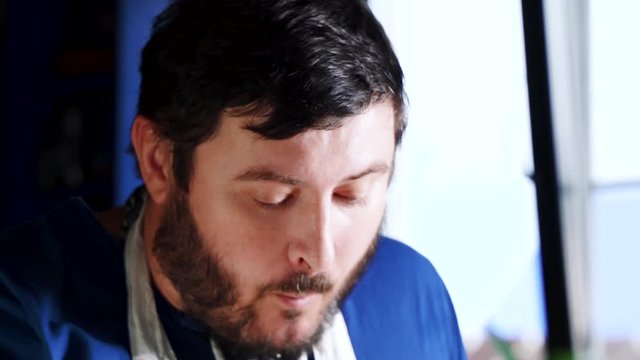 Happy smiling adalt man with beard eating a delicious french fries. Hungry young guy at cafe enjoys eating, chewing. Fast food restaurant concept. Close up