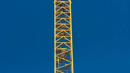 gelber Baukran vor blauem Himmel, Blick von unteen