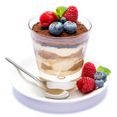 Classic tiramisu dessert with blueberries and raspberries in a glass isolated on a white background with clipping path