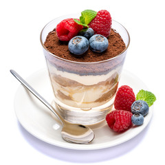 Classic tiramisu dessert with blueberries and raspberries in a glass isolated on a white background with clipping path