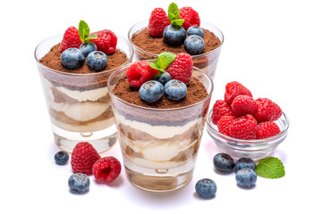Classic tiramisu dessert with blueberries and raspberries in a glass isolated on a white background with clipping path