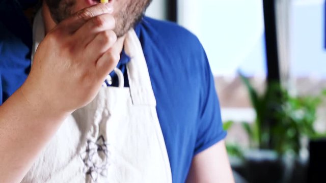 Happy smiling adalt man with beard eating a delicious french fries and onions. Hungry young guy at cafe enjoys eating, chewing. Fast food restaurant concept. Close up