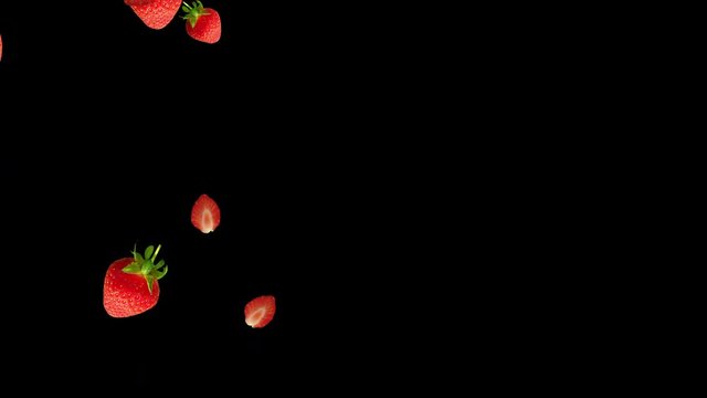 Strawberries falling down against black background with space for your text. Healthy eating concept