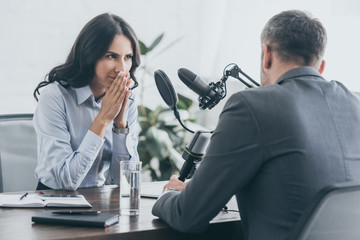 attentive radio host itterviewing businessman in broadcasting studio