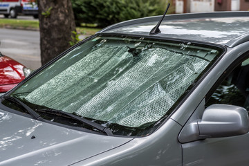 Sun reflector on the windscreen or windshield as protection of the car plastic indoor panel from direct sunlight and heat