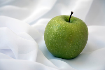 Green apple on a white background, with water droplets