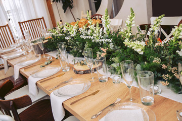 The table in the interior of the cafe is decorated with natural wood elements and fresh bouquets of flowers. Cutlery on the table.