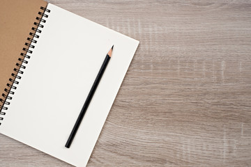 Top view, blank book and pencil on blank book on the wooden table.