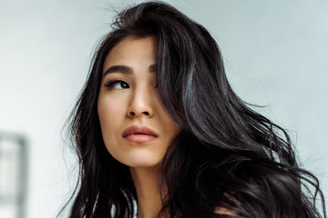 Naklejka premium attractive and dreamy asian woman thinking at home