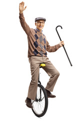 Senior man riding a unicycle and holding a walking cane © Ljupco Smokovski