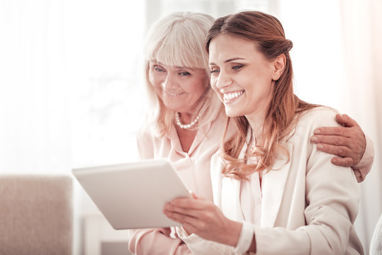 Two smiling happy women looking through the family pictures on a tablet