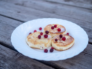 pancakes with wild berries on a white plate on a wooden background