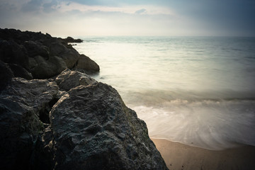 beautiful sandy scenic beach in sunset, with rocky breakwater in long exposure in basque country,...