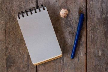Spiral notepad blank page and pen on wooden background. Empty sketchbook top view photo. Grey paper...