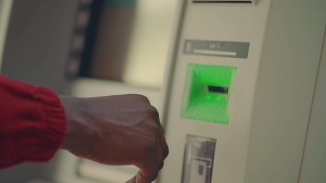 Close up view of Afro-American businessman waiting for cash from ATM after inserting card and entering pin code. Cash withdrawal, daily life, finance and people concept