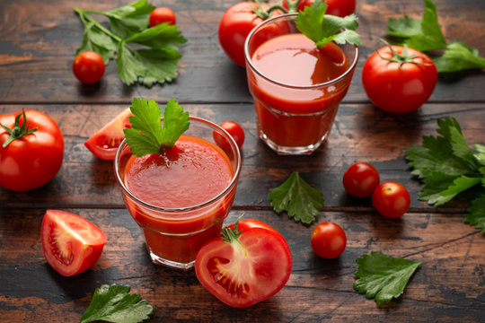 Tomato juice in glass with celery on rustic wooden table