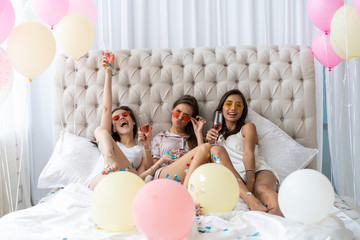 Pajama party. Attractive young smiling women in pajamas drinking champagne while having a slumber...
