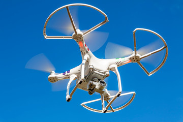 Quadrocopter with a camera in flight against a blue sky.