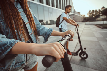 Obraz premium Closeup photo shoot of girls hands on the electro scooter's steering wheel.