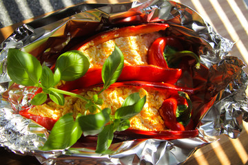 Close up of stuffed red paprika bell peppers with sheep feta cheese seasoned with spicy chili grilled in aluminium foil