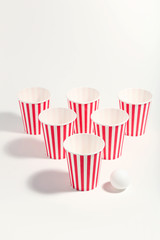 Striped paper cups and ball on white background. Minimalism concept
