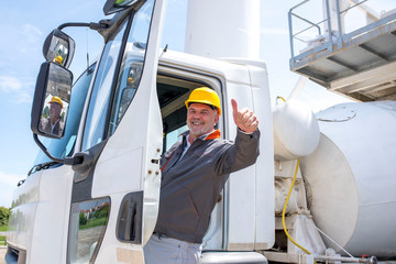 Concrete mixer truck driver with thumb up enters the cabin of his truck