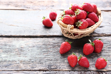 Fresh strawberries in basket on grey wooden table