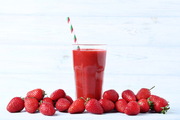 Smoothie in glass with strawberries on wooden table