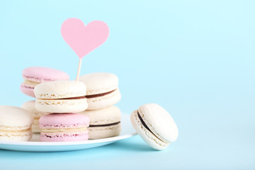 Sweet macarons with paper heart on blue background. Minimalism concept