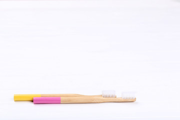 Bamboo toothbrushes on white wooden table