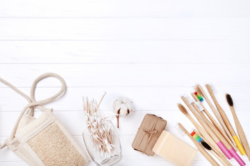 Bamboo toothbrushes with soap, washcloth and cotton sticks on white wooden table