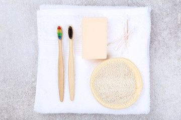 Bamboo toothbrushes with soap, sponge and cotton sticks on grey background