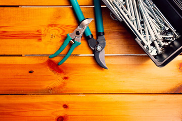 Two pairs of pruning scissors and a tool box are laying on a wooden surface