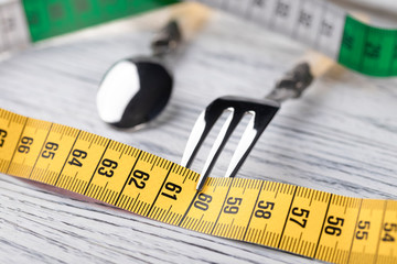 A multi-colored centimeter wrapped a dessert fork on an old wooden table showing the number 60