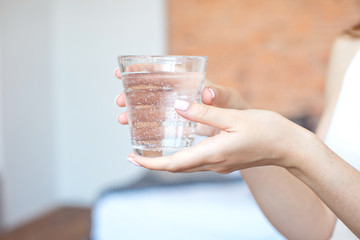 Female hands holding a clear glass of water.A glass of clean mineral water in hands, healthy drink