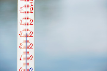 Thermometer during hot weather with water in background