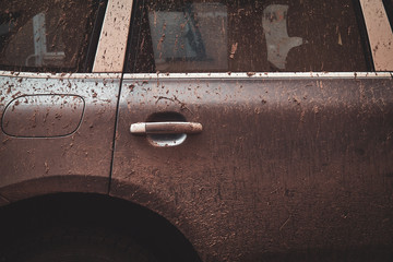Closeup photo shoot of dirty car's door and window, splash of mud on silver car.