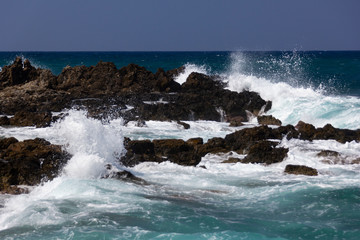 sea waves beating on the rocks near the shore, white sea foam waves against the turquoise sea