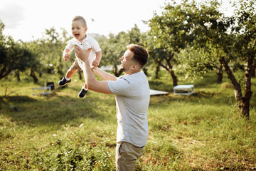 Happy young father with little son play in the park at summer