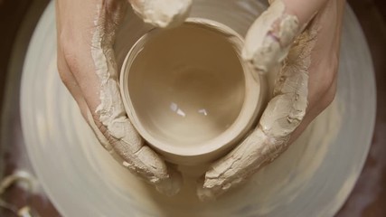  close-up of a Potter's hand sculpts a pot pitcher of clay on a Potter's wheel