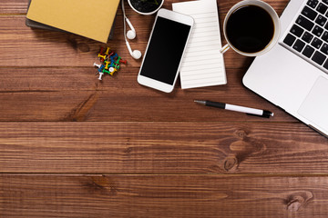 Wood office desk table with laptop, cup of coffee and supplies.