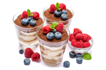 Classic tiramisu dessert with blueberries and raspberries in a glass isolated on a white background with clipping path