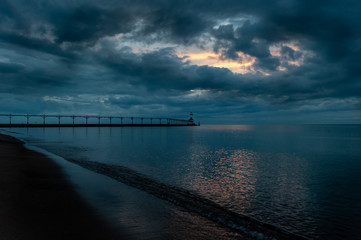 Obraz premium Stormclouds part over lighthouse along beach in michigan city indiana